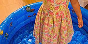 Denali is registered to the contest to win money with this photo: basketball, child, colorful, curly_hair, curtain, dress, elmo_toy, furniture, girl, happy, home, indoor, inflatable_pool, living_room, playful, puddle_pool, smiling, toy, toy_basketball, wooden_floor