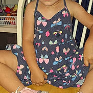 Denali is registered to the contest to win money with this photo: butterfly_pattern, calm_expression, casual_clothing, chair, child, colorful, curly_hair, cute, dress, feet, footwear, furniture, indoor, looking_at_camera, person, pink_shoes, portrait, sitting, wooden_floor, young