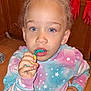 blue_eyes, casual, child, curly_hair, expression, face, floor, hand, indoor, kitchen, mouth, pastel_clothing, person, portrait, red_gloves, star_pattern, sweatshirt, toothbrush, wooden_cabinets, young_child