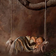 Atticus is registered to the contest to win money with this photo: baby, sleeping, blanket, swing, tree_branch, fur, knitted, cozy, peaceful, portrait, infant, child, nature, woodland, soft_texture, brown_background, rest, cute, newborn, calm