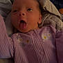 Adelia is registered to the contest to win money with this photo: baby, infant, tongue_out, purple_clothing, floral_embroidery, blanket, cozy, cute, sleepwear, child, indoors, portrait, newborn, expression, soft_lighting, person, baby_girl, playful, lying_down, fabric