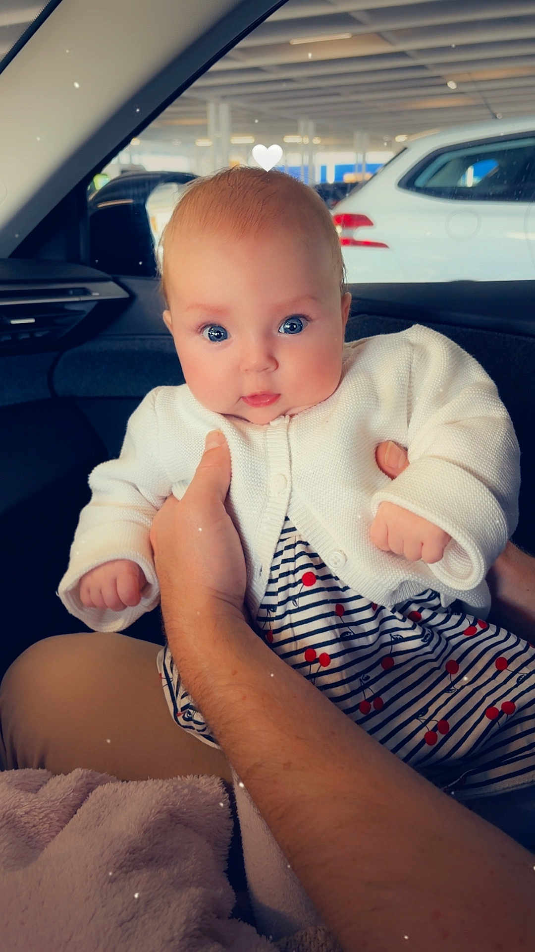 Eleanor participe au concours pour gagner de l'argent avec cette photo : baby, infant, child, person, face, blue_eyes, white_cardigan, striped_dress, red_dots, hand, car_interior, car_window, parking_lot, vehicle, cute, adorable, chubby_cheeks, holding, heart_filter, portrait