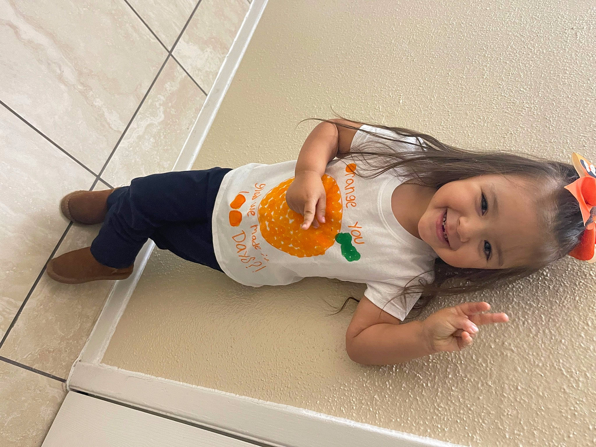 Katherine is registered to the contest to win money with this photo: baby_toddler_clothing, child, floor, flooring, foot, fun, human_leg, joy, knee, person, room, sitting, sleeve, smile, sock, t_shirt, thigh, toddler, wood