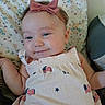 baby, infant, headband, bow, dress, usa_flag, pattern, floral_blanket, smile, face, skin, arm, lying_down, cute, child, indoors, fabric, person, apparel, textile
