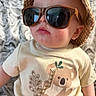 Michael is registered to the contest to win money with this photo: baby, child, sunglasses, hat, bucket_hat, koala, tshirt, plaid, patterned_blanket, cute, fashion, portrait, indoor, infant, casual_clothing, young_child, face, headwear, soft_fabric, pout