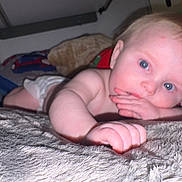 Michael is registered to the contest to win money with this photo: baby, infant, blue_eyes, diaper, hand, face, indoor, lying_down, soft_texture, blanket, cushion, curious, closeup, child, person, skin, head, young, comfort, resting