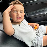 Nicolas joined the competition — help win amazing prizes! child, boy, car, car_seat, orange, fruit, shorts, white_shirt, hand, hair, expression, leather, interior, seatbelt, casual_clothing, portrait, young, candid, sitting, food