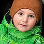 beanie, brown_hat, cheeks, child, closeup, cute, eyebrows, eyes, face, green_jacket, hood, outfit, portrait, seat, smile, stroller, toddler, warm_clothing, winter, winter_jacket