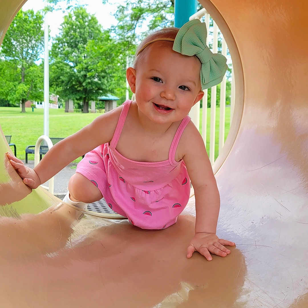 Serenity is registered to the contest to win money with this photo: baby, baseballcap, cap, clothing, face, grass, hat, head, nature, outdoorplayarea, outdoors, park, person, photography, plant, playarea, portrait, slide, summer, toy