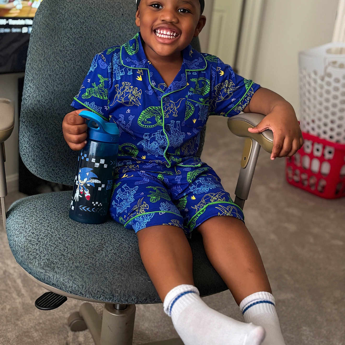 Daceon joined the competition — help win amazing prizes! child, smiling, pajamas, dinosaur, blue, chair, water_bottle, sonic_the_hedgehog, indoor, carpet, laundry_basket, television, cartoon, happy, socks, headwear, person, furniture, room, home