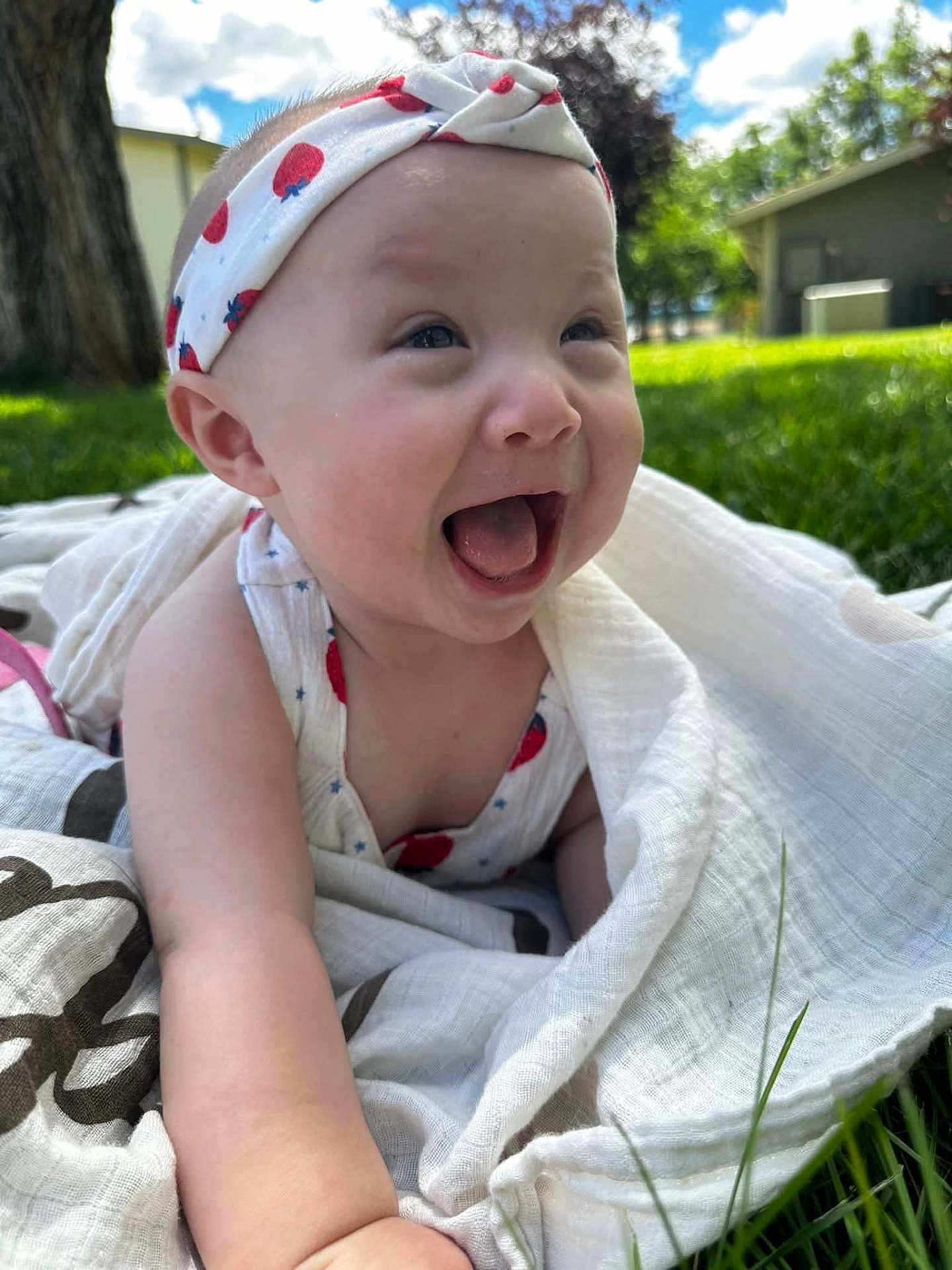 Sequoia is registered to the contest to win money with this photo: baby, infant, headband, smiling, happy, outdoor, grass, blanket, sunny, daylight, nature, child, cute, portrait, head, person, clothing, face, expression, summer