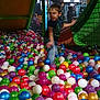 child, boy, ball_pit, playground, indoor, plastic_balls, colorful, netting, play_area, motion_blur, casual_clothing, short_hair, fun, active, recreation, childhood, entertainment, young, play, smiling
