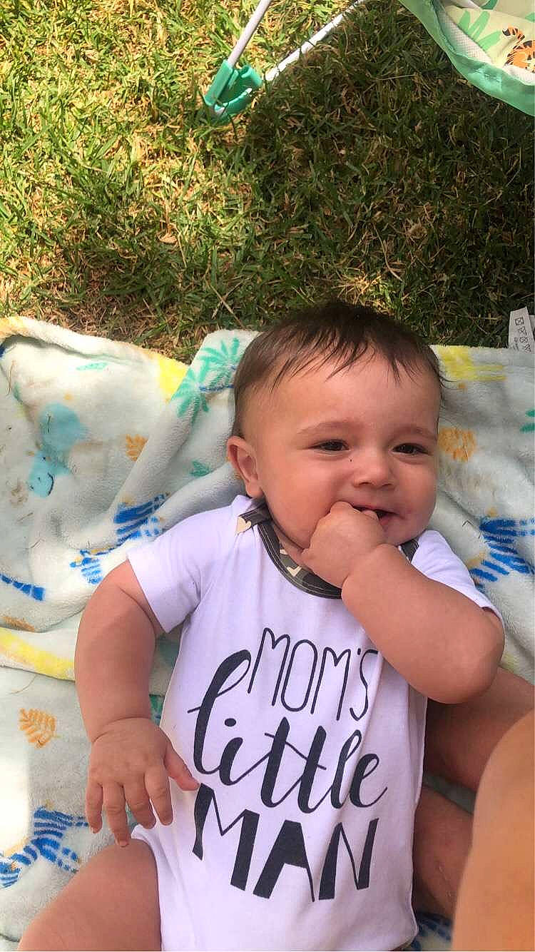Dasan is registered to the contest to win money with this photo: baby, baby_products, baby_toddler_clothing, cheek, child, facial_expression, finger, fun, grass, green, handwriting, happy, leisure, person, product, sitting, skin, sleeve, smile, t_shirt