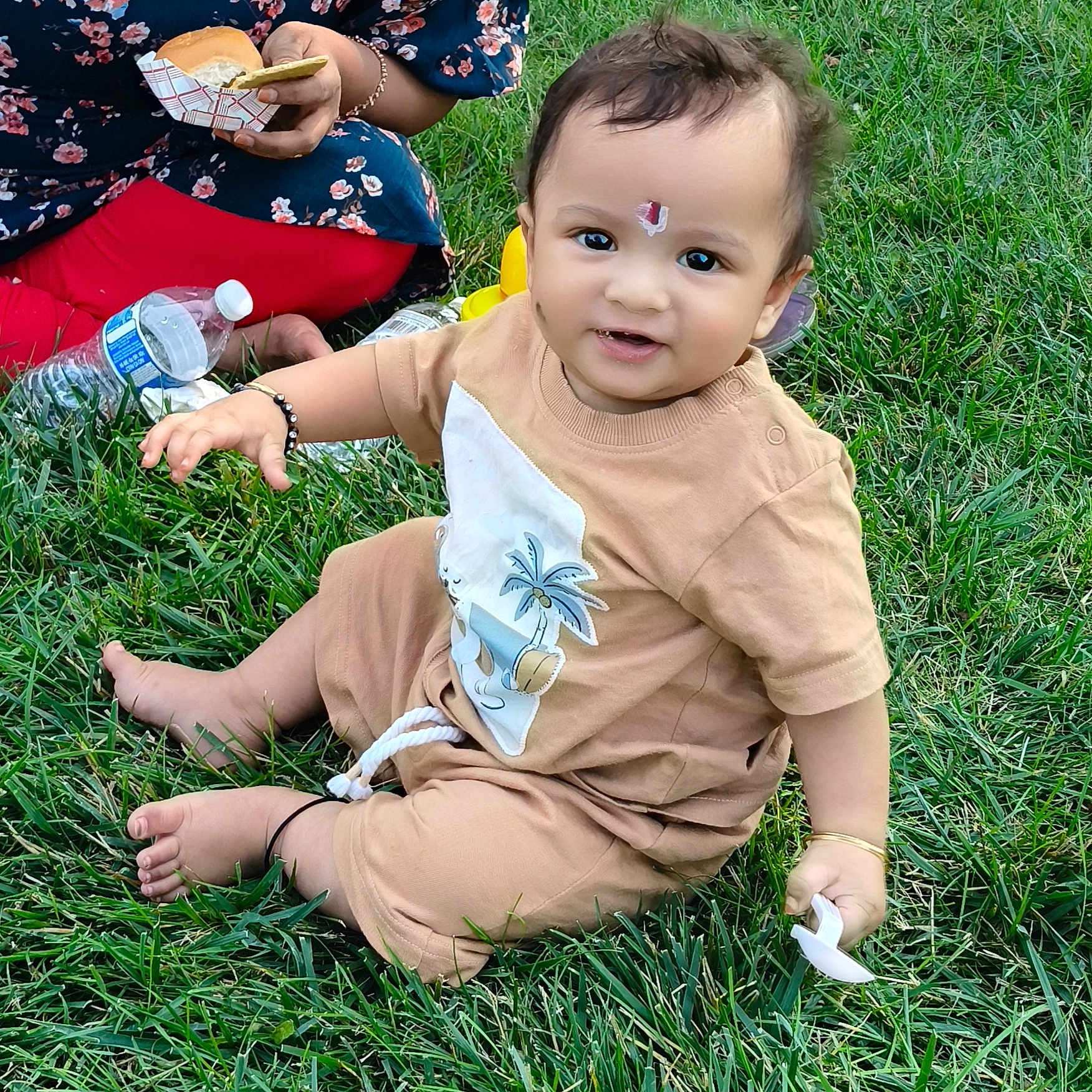 Praneeth Thunugunta is registered to the contest to win money with this photo: adult, baby, barefoot, beige_outfit, bracelet, bracelet_black, casual, child, floral_dress, food, grass, happy, nature, outdoor, pacifier, picnic, red_leggings, sandwich, sitting, smiling