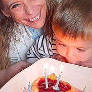 Samael participe au concours pour gagner de l'argent avec cette photo : woman, child, birthday, cake, candles, celebration, dessert, food, plate, happy, smiling, curly_hair, striped_shirt, indoor, table, closeup, family, home, light, face