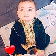 Youcef Ilyane participe au concours pour gagner de l'argent avec cette photo : baby, child, velvet_clothing, gold_embroidery, couch, blanket, indoor, curious, sitting, face, hand, expression, heart_emoji, soft_lighting, portrait, young_child, cute, decor, fabric, home