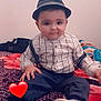 baby, bed, blanket, child, cute, face, fashion, hat, indoor, pants, pattern, person, portrait, red_heart_emoji, shirt, shoe, sitting, smile, sock, suspenders