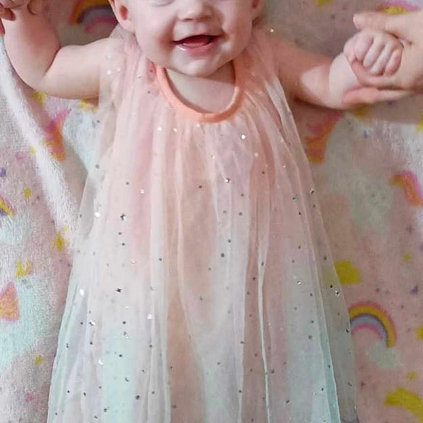 Emma is registered to the contest to win money with this photo: accessories, baby, babylaughing, bodypart, clothing, costume, dress, face, happy, head, jewelry, laughing, mouth, necklace, newborn, person, photography, portrait, smile, teeth