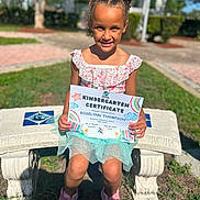 Roselynn joined the competition — help win amazing prizes! bench, celebration, certificate, child, cute, daytime, dress, girl, grass, hairstyle, happy, kindergarten, nature, outdoor, person, pink_shoes, portrait, school, smiling, sunny