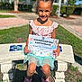 Roselynn joined the competition — help win amazing prizes! child, girl, certificate, kindergarten, outdoor, bench, smile, sunlight, dress, shoes, grass, hair_buns, happy, school, achievement, person, portrait, daytime, nature, celebration