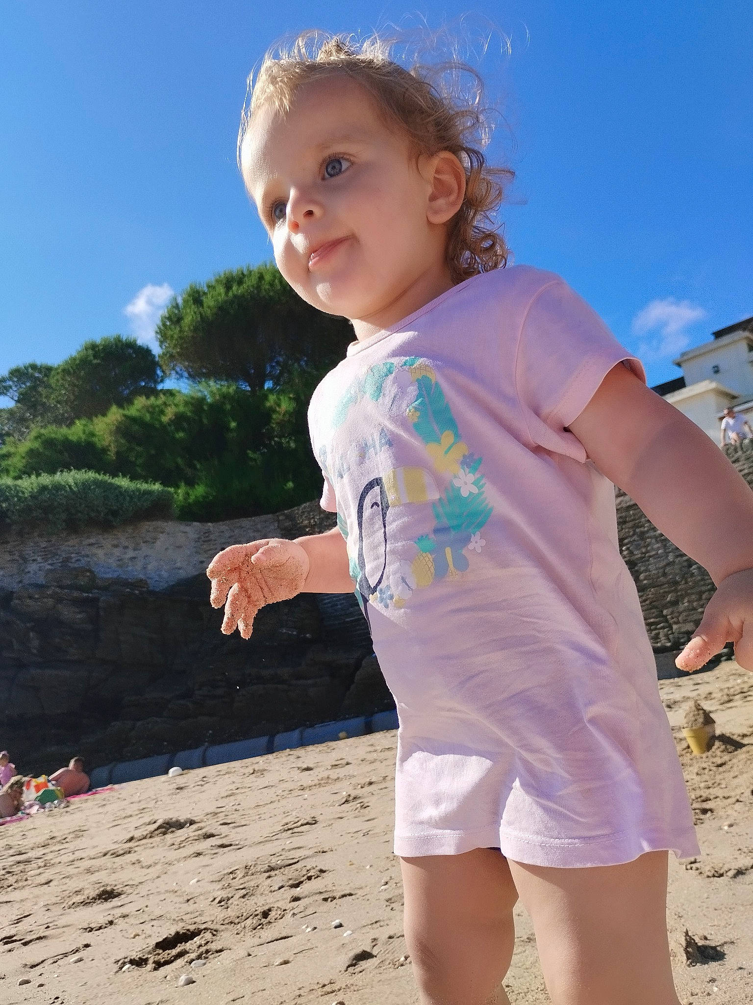 Malak a rejoint le concours — aidez-le/la à gagner de superbes lots ! beach, body_of_water, child, cloud, flash_photography, fun, gesture, grass, happy, leisure, people_in_nature, people_on_beach, person, sky, sleeve, smile, standing, sunlight, t_shirt, toddler