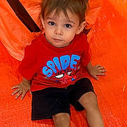 Alex is registered to the contest to win money with this photo: child, toddler, boy, portrait, sitting, orange_tent, red_shirt, spiderman, shorts, indoor, play tent, brown_hair, wide_eyes, looking_at_camera, hands, legs, colorful, candid, happy, safe