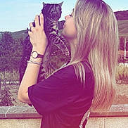 Ulyana participe au concours pour gagner de l'argent avec cette photo : woman, cat, outdoor, sky, nature, blonde_hair, holding, affection, tabby_cat, casual_clothing, watch, bracelet, wall, greenery, summer, daylight, portrait, side_view, smile, human_pet_interaction