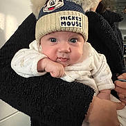 Sacha participe au concours pour gagner de l'argent avec cette photo : adult, baby, black_jacket, child, closeup, clothing, cozy, cute, expression, face, hand, hat, holding, indoor, mickey_mouse, person, pom_poms, portrait, warm, white_outfit