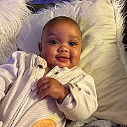 Verity Reign is registered to the contest to win money with this photo: baby, infant, child, smiling, portrait, close_up, indoors, pillow, cushion, blanket, stuffed_animal, elephant, white_clothing, onesie, sitting, lying_down, face, eyes, happy, cozy