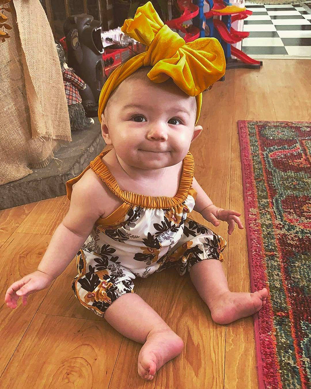 Cataleya is registered to the contest to win money with this photo: baby, child, child_model, clothing, costume, dress, fashion_accessory, fawn, floor, flooring, hair_accessory, headband, headgear, person, toddler, wood, yellow