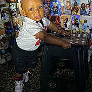 Kyaire joined the competition — help win amazing prizes! toddler, child, boy, sneakers, white_shirt, black_shorts, stool, indoor, photo_wall, family_photos, curious, standing, hands_on_stool, wide_eyes, expression, floor, portrait, casual_clothing, young_child, cute