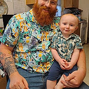 Garreth joined the competition — help win amazing prizes! baby, beard, cabinet, cartoon, casual, chair, child, floor, glasses, happy, holding, indoor, kitchen, man, pattern, person, shirt, smile, tattoo, window