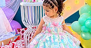 Naslhey is registered to the contest to win money with this photo: child, toddler, birthday, birthday_cake, party, dress, pastel, balloons, presents, gift_bags, smiling, portrait, standing, girl, curly_hair, braids, outdoor, colorful, decorations, number_backdrop