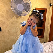 Naslhey is registered to the contest to win money with this photo: child, girl, portrait, smiling, indoors, blue_dress, princess_dress, hair_bow, braided_hair, bed, bedspread, wall_fan, bedroom, decor, portrait_photography, posing, happy, jewelry, ballet_style, home_interior
