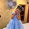 child, girl, portrait, smiling, indoors, blue_dress, princess_dress, hair_bow, braided_hair, bed, bedspread, wall_fan, bedroom, decor, portrait_photography, posing, happy, jewelry, ballet_style, home_interior