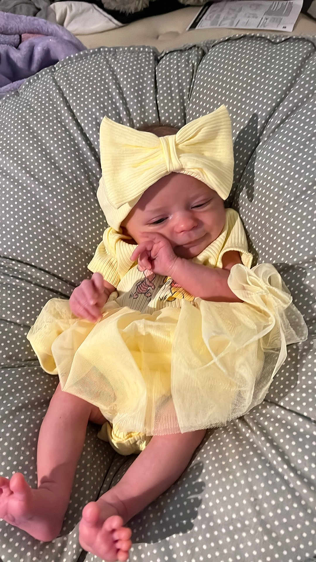 Aurora joined the competition — help win amazing prizes! baby, infant, yellow_dress, headband, bow, polka_dot, cushion, sleepy, cute, small_feet, newborn, soft, indoors, child, person, apparel, fabric, relaxing, resting, cozy