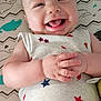 baby, smiling, infant, onesie, patterned_clothing, hands, tongue_out, lying_down, mattress, whale_pattern, zigzag_pattern, cute, happy, child, indoor, closeup, skin, head, face, playful