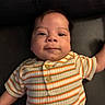baby, infant, child, portrait, face, smiling, eyes, lying_down, striped_shirt, clothing, orange, green, white, couch, indoor, close_up, photography, arms, soft_lighting, adorable