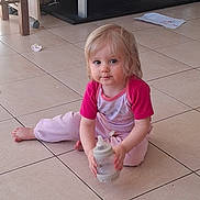 Aude Reze participe au concours pour gagner de l'argent avec cette photo : toddler, child, baby_bottle, pacifier, floor, tile, indoor, furniture, drawing, paper, pink_clothing, blonde_hair, curious_eyes, sitting, barefoot, person, young_child, casual, home, cute