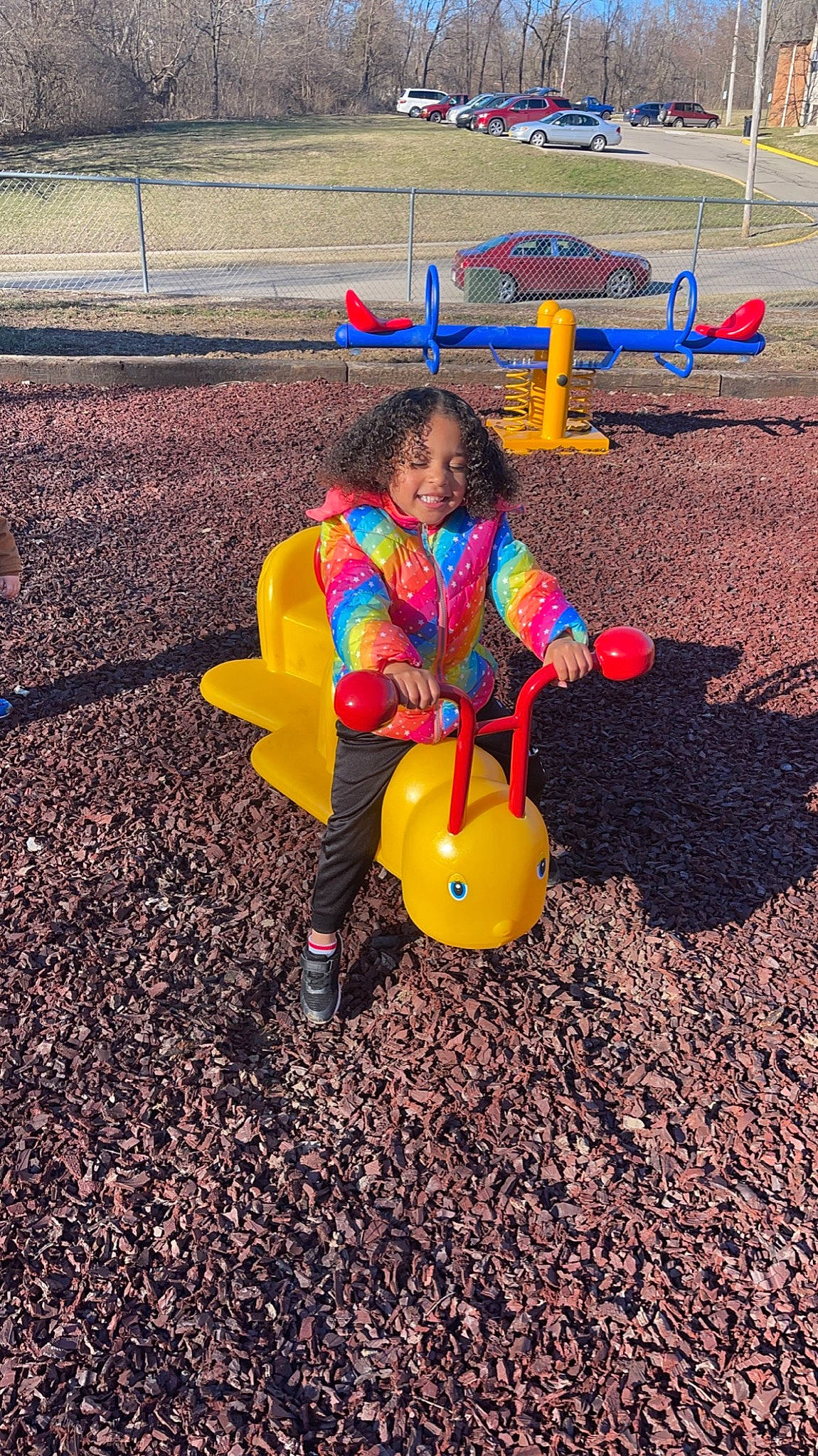 Aryanna is registered to the contest to win money with this photo: asphalt, child, city, fun, grass, happy, joy, landscape, leisure, outdoor_play_equipment, people_in_nature, person, play, playground, recreation, road_surface, shadow, sitting, smile, soil