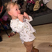 Swann participe au concours pour gagner de l'argent avec cette photo : bag, boots, brown_pants, child, doll, flash_red_eye, hair_bun, hardwood_floor, indoor, living_room, lollipop, messy_room, playing, portrait, side_profile, sofa, standing, toddler, toy, white_shirt