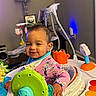 baby, child, infant, smiling, portrait, indoor, activity_center, baby_toys, colorful_toys, playroom, sitting, onesie, bib, high_chair, mobile_toy, swing, lamp, home, happy, photography