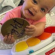 Areonna joined the competition — help win amazing prizes! baby, infant, child, smiling, happy, portrait, close_up, face, eyes, pink_shirt, sitting, activity_center, toy, handwritten_sign, milestone, indoor, playtime, colorful, family_photo, safe