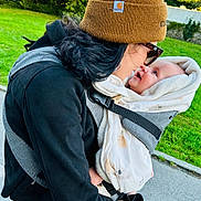 Abby participe au concours pour gagner de l'argent avec cette photo : baby, adult, beanie, black_hair, blue_jeans, carrier, child, clothing, face, gloves, greenery, happy, hug, jacket, outdoor, person, sunglasses, toddler, walkway, warm_clothing
