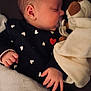 baby, black_clothing, blanket, child, close_up, cozy, cute, face, hand, heart_pattern, indoors, infant, newborn, pacifier, peaceful, plush_toy, resting, sleeping, soft_texture, warm_lighting