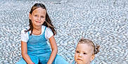 Victoire participe au concours pour gagner de l'argent avec cette photo : child, children, toddler, sitting, outdoor, cobblestone, stone_wall, archway, gate, blue_outfit, shorts, overalls, white_shirt, footwear, smile, hair, person, daylight, urban, casual