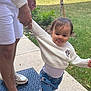 Skylar is registered to the contest to win money with this photo: toddler, child, adult_hand, sidewalk, grass, white_sweater, minnie_mouse, blue_pants, shoes, outdoor, playful, tongue_out, person, holding_hand, casual_clothing, shorts, greenery, daylight, walking, cute