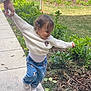 Skylar is registered to the contest to win money with this photo: toddler, child, white_sweater, minnie_mouse, blue_pants, cartoon_print, sneakers, sidewalk, greenery, outdoor, grass, plants, hand_holding, playful, happy, person, walking, sunlight, garden, curly_hair