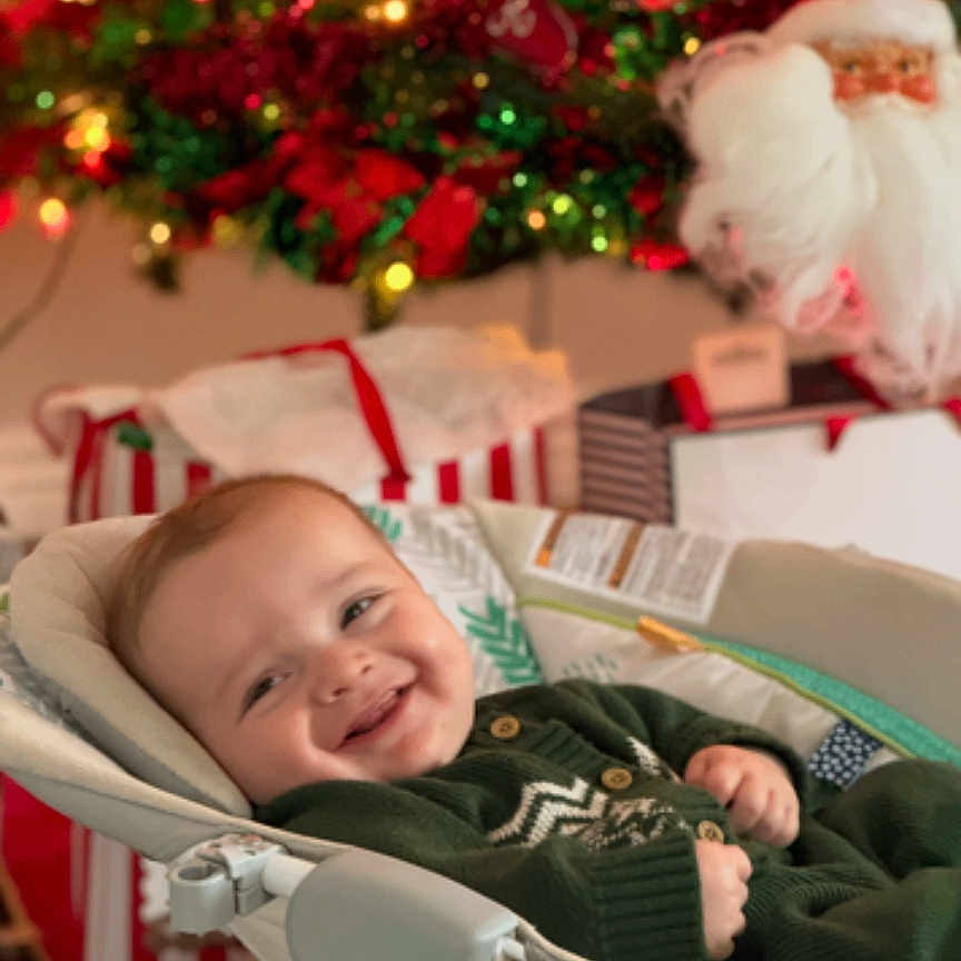 Rowan is registered to the contest to win money with this photo: baby, baby_seat, celebration, child, christmas_lights, christmas_tree, cozy, cute, festive, gift_boxes, green, happy, holiday, indoors, infant, ornaments, red, santa_decoration, seasonal, smiling