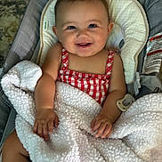 Mari is registered to the contest to win money with this photo: baby, baby_seat, blanket, checkered, child, clothing, comfort, cozy, cute, face, hands, happy, indoors, infant, person, photography, portrait, red_and_white, smiling, young
